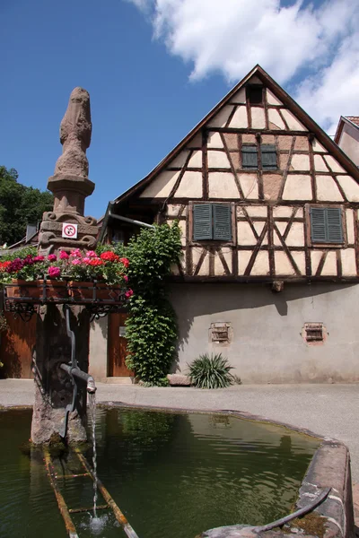 Village fountain with with half-timbered house — Stock Photo, Image
