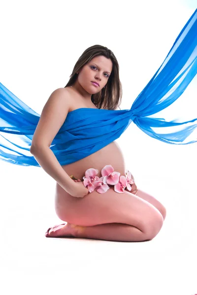 Pregnant young woman in fabric with orchid — Stock Photo, Image