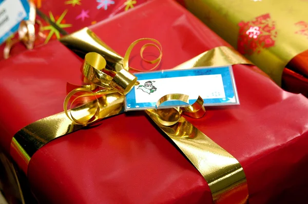 Red Christmas present with gold ribbon and tag — 图库照片