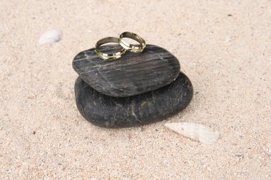 Wedding rings on black pebbles clipart