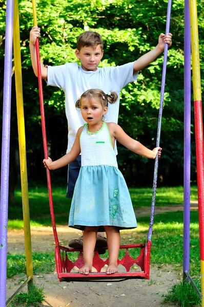 De jongen en het meisje op een schommel — Stockfoto