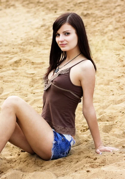 Schönes Mädchen sitzt auf Sand — Stockfoto