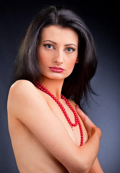 Beautiful dark haired girl with red beads — Stock Photo, Image