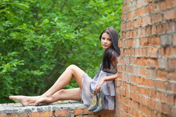 Девушка сидит на старой стене — стоковое фото