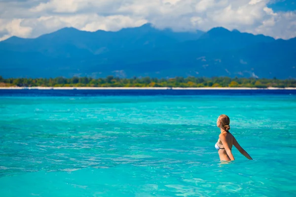 Woman wearing white bikini facing the sea on a vacant beach in paradise — Stock Photo, Image