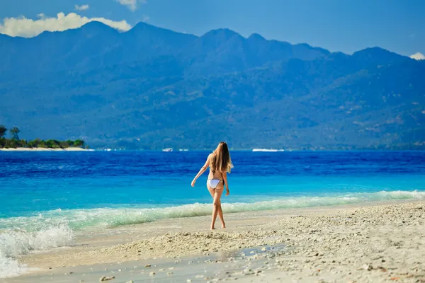 낙원에 있는 빈 해변에서 바다를 마주 하는 흰색 비키니를 입고 여자 — 스톡 사진