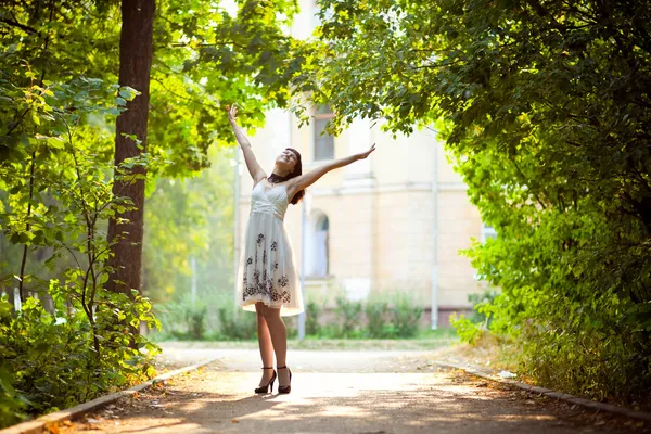 Молода жінка підняла руки насолоджуючись свіжим повітрям у зеленому лісі . — стокове фото