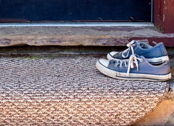 Chaussures de tennis bleu sur tapis de porte — Photo