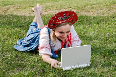 Çimlerin üstünde a laptop ile ulusal giysileri kızı
