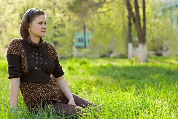 Fiatal gyönyörű nő ül a fűben — Stock Fotó