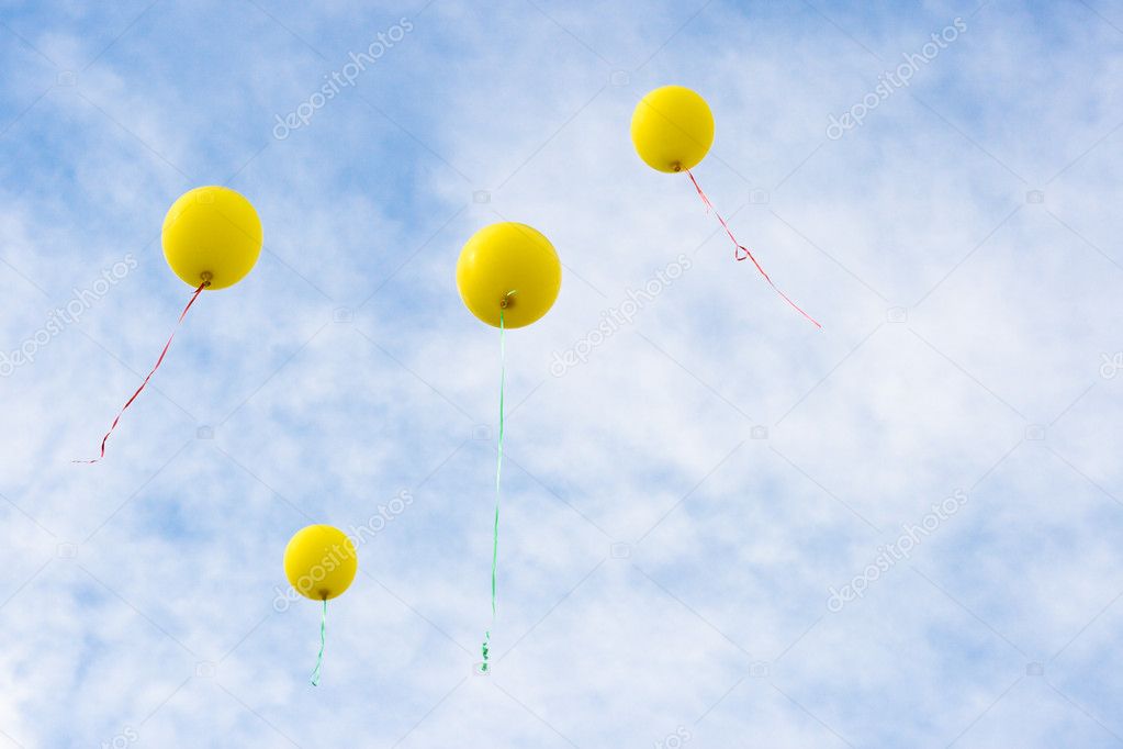 Four yellow baloons rising