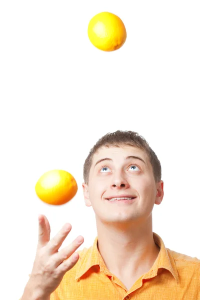 Young adult man juggle with oranges — Stock Photo, Image