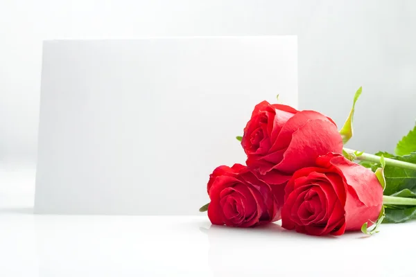 Three roses with blank paper card — Stock Photo, Image