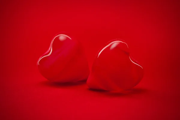 Zwei rote Herzen auf rotem Hintergrund — Stockfoto