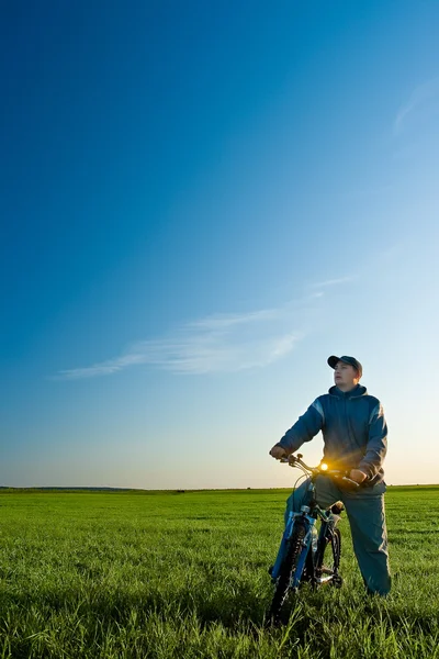 Homem de bicicleta no campo verde — Fotografia de Stock
