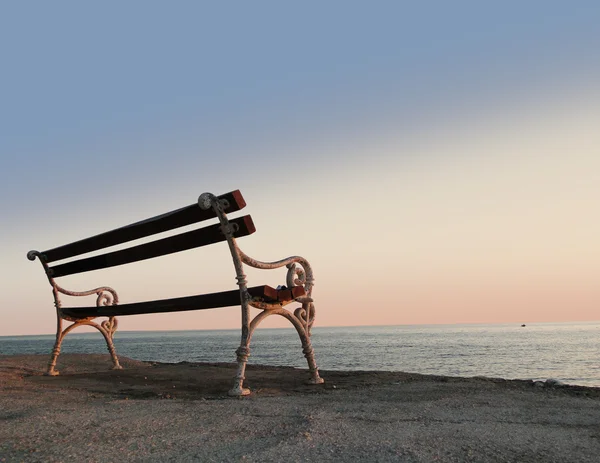 在日落海旁的长凳上 免版税图库照片