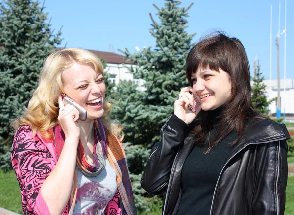 Two girls call by phone in a park — Stock Photo, Image