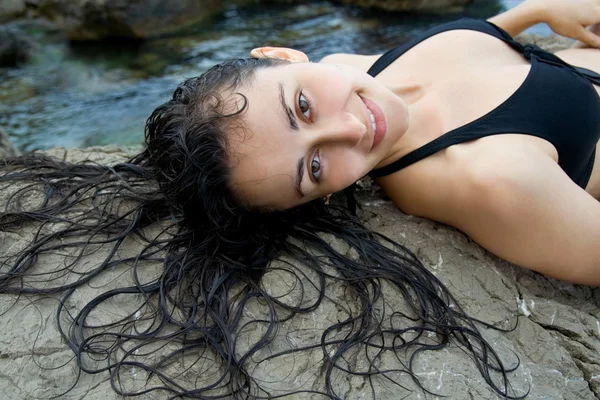 Zbliżenie ładny dziewczyna leżąc na skale w pobliżu morza — Zdjęcie stockowe