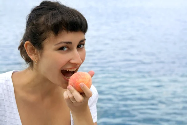 Красива дівчина їсть персик — стокове фото