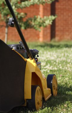 Yellow lawn mower on green grass clipart