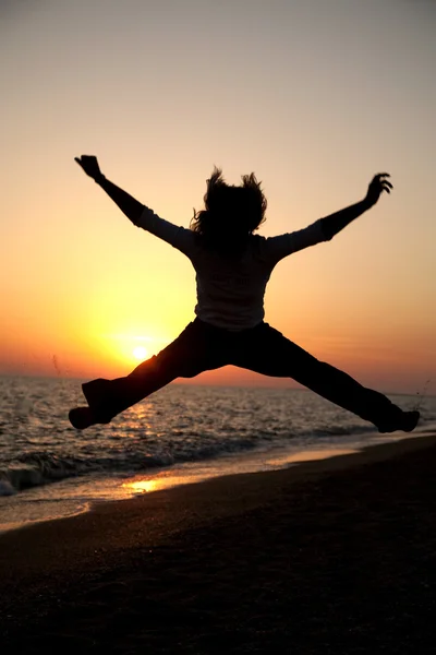 Jeune fille adulte sauter au coucher du soleil — Photo