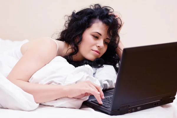 Porträtt av kvinna i sängen med laptop — Stockfoto