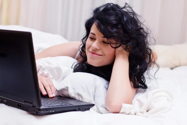 Portret van vrouw tot in bed met laptop — Stockfoto