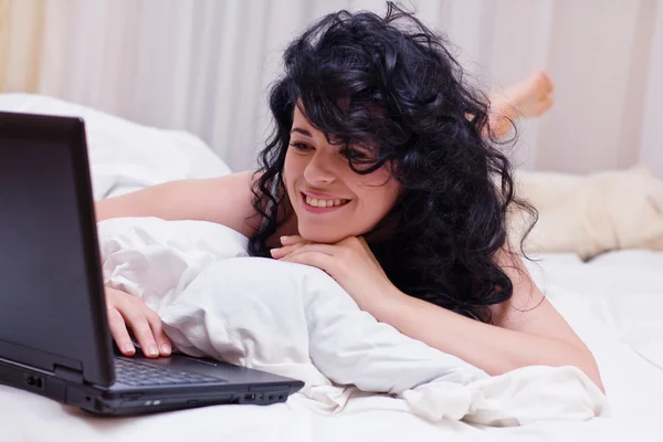 Porträt einer Frau, die mit Laptop im Bett liegt — Stockfoto
