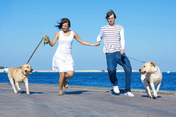 Casal jovem correndo com cães — Fotografia de Stock