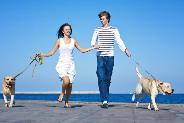 Casal jovem correndo com cães — Fotografia de Stock