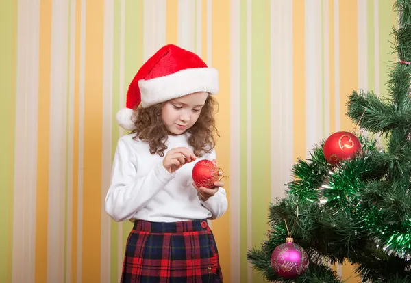 Kleines Mädchen mit Spielzeug in der Nähe des Weihnachtsbaums — Stockfoto
