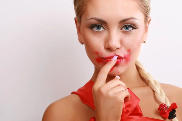 Woman smearing lipstick on face — Stock Photo, Image