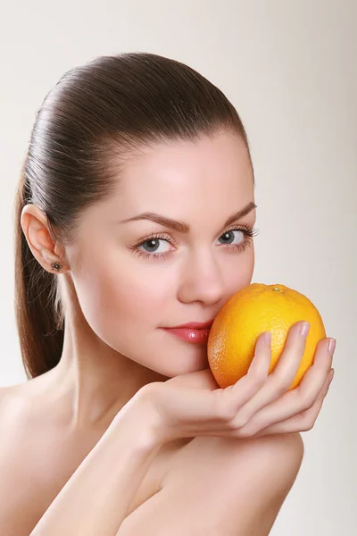 Attractive woman holding orange in studio — Stock Photo, Image