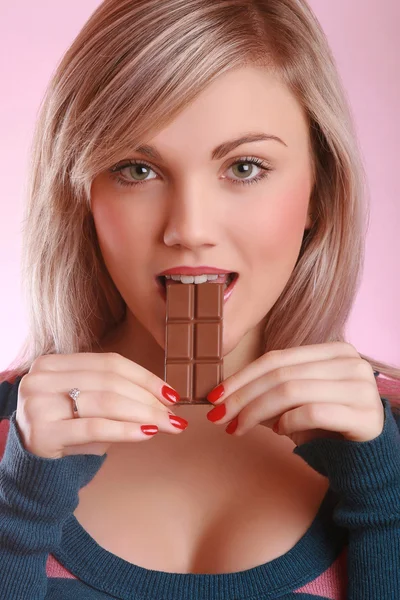 Jovem adulto morde barra de chocolate — Fotografia de Stock