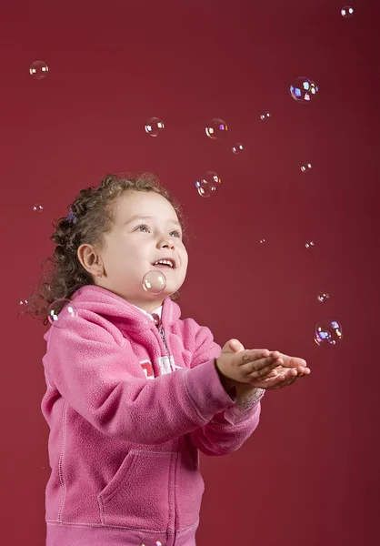 Девочка ловит мыльные пузыри — стоковое фото