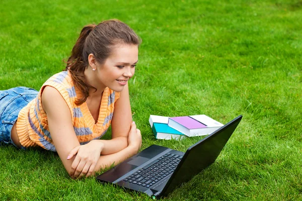 Flicka på gräs med laptop — Stockfoto
