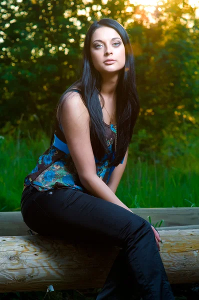 Young woman sitting on a log — Stock Photo, Image