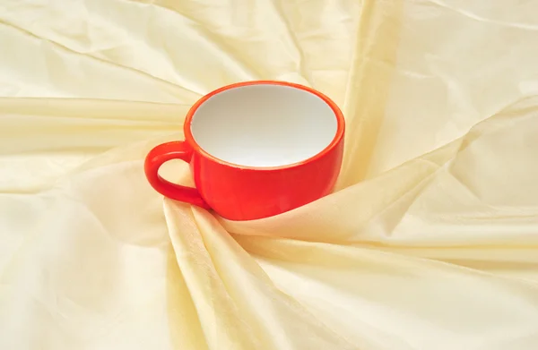 Red cup at the golden fabric drapery