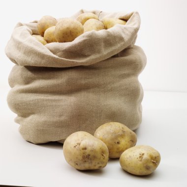 Overflowing bag of potatoes on whit clipart