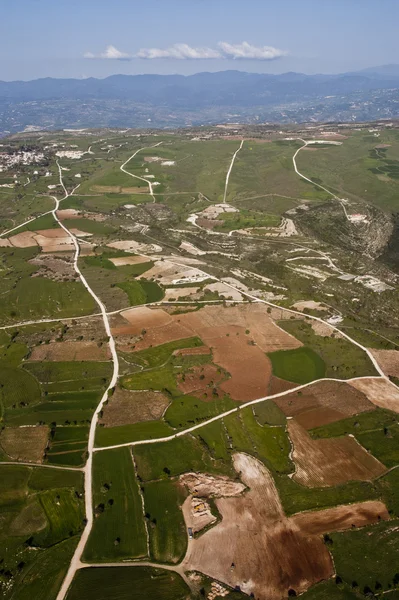 Vista aérea em campos agrícolas em frente a montanhas nebulosas — Fotografia de Stock
