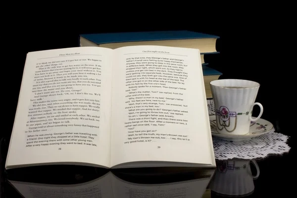 Filiżankę herbaty i książek na czarnym tle — Zdjęcie stockowe