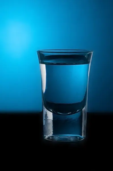 Glass of vodka on blue background — Stock Photo, Image