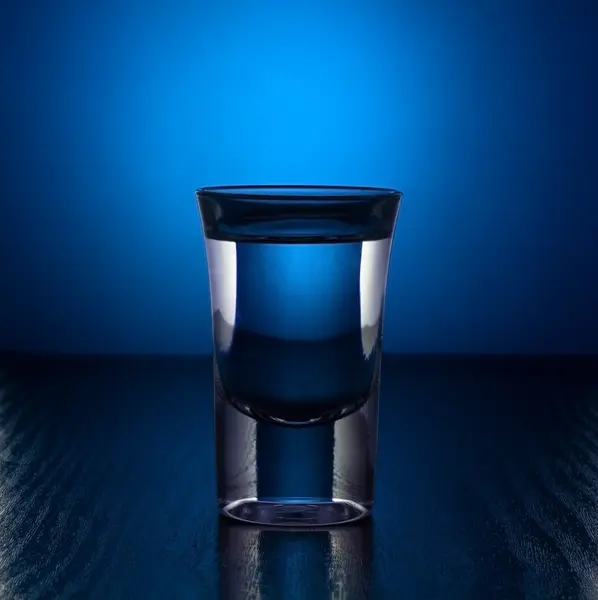 Vaso de vodka sobre fondo azul — Foto de Stock