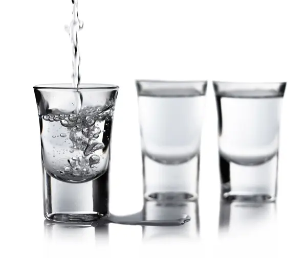 Esguichando água derramando em um copo Imagem De Stock