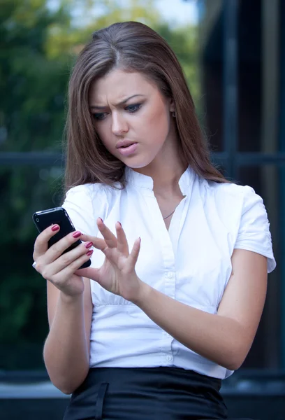 Young woman looks in phone and is angry — Stock Photo, Image
