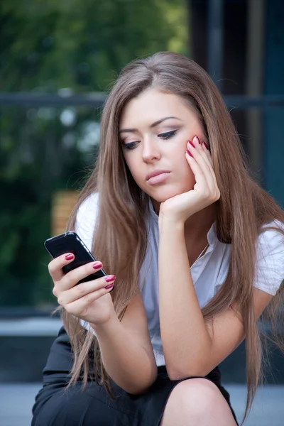 Young woman looks in phone and longs having seen something on th — Stock Photo, Image