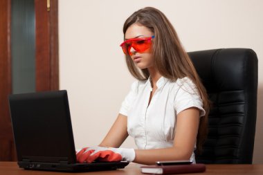 Young woman behind a table with the laptop in gloves and orange clipart