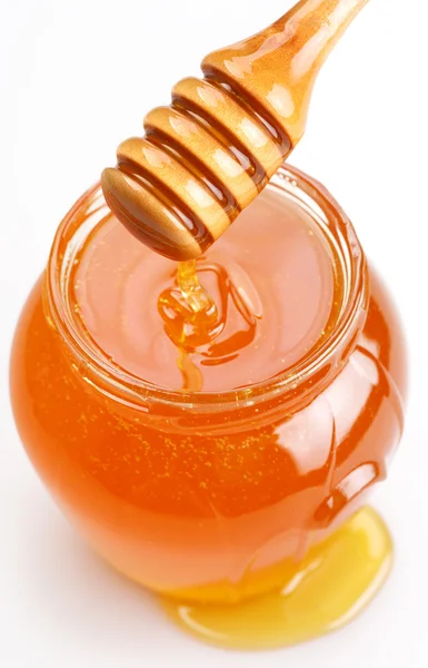Panela de mel completa e mel derramado em um fundo branco . — Fotografia de Stock