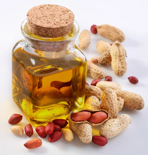 Óleo de amendoim com nozes sobre um fundo branco — Fotografia de Stock