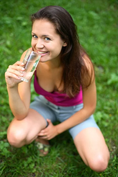 En tjej dricker vatten ur glas. — Stockfoto
